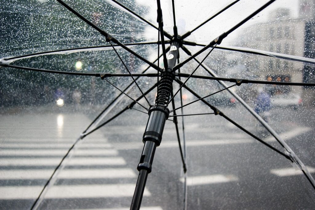Rue pavée de Bordeaux sous la pluie avec un parapluie et les façades du vieux quartier